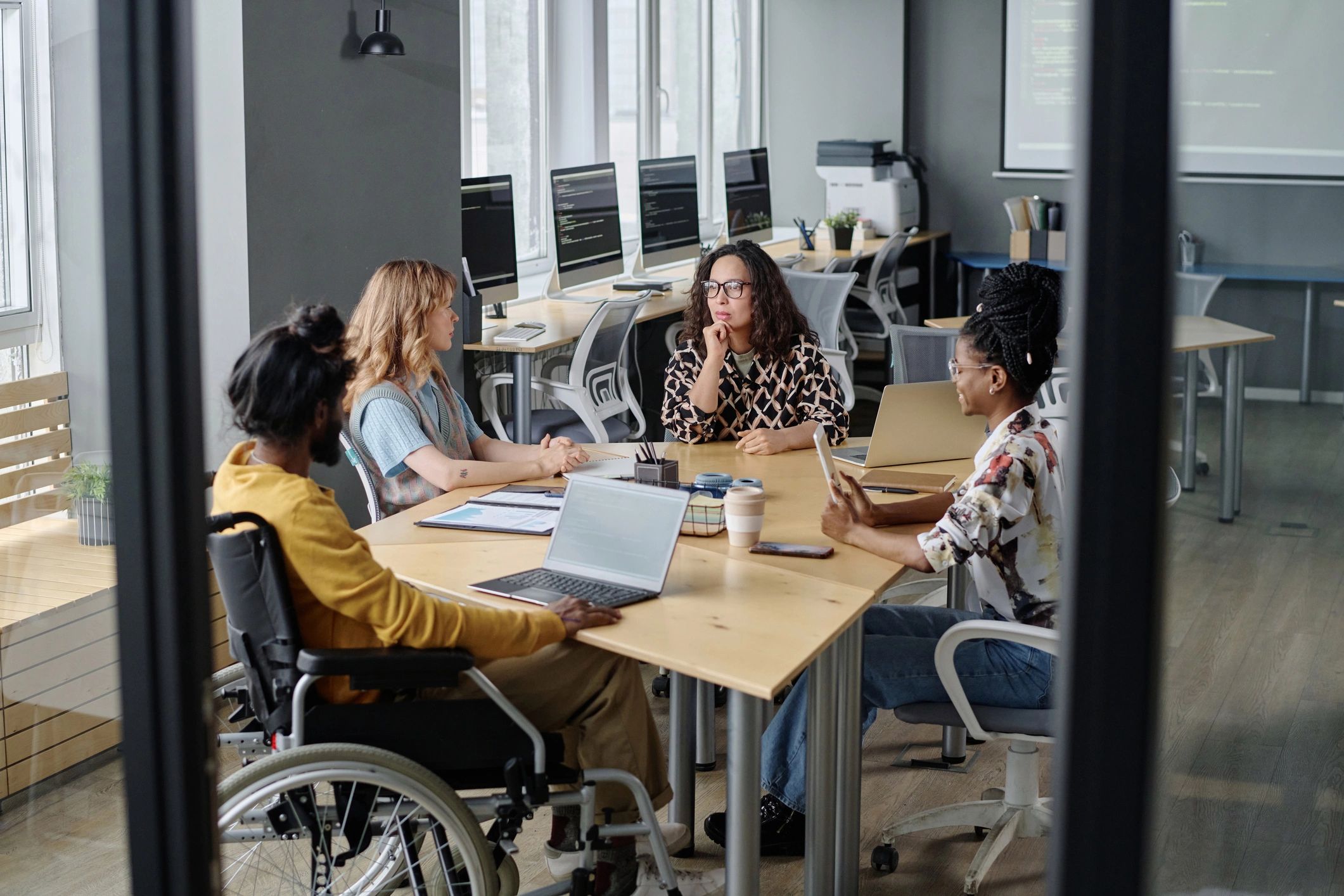 Inclusive team meeting with a wheelchair user collaborating at a desk
